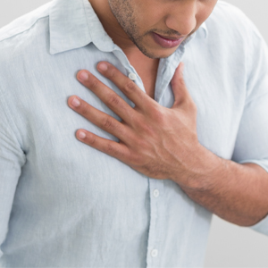 Man holding chest from burning sensation caused by GERD (acid reflux).